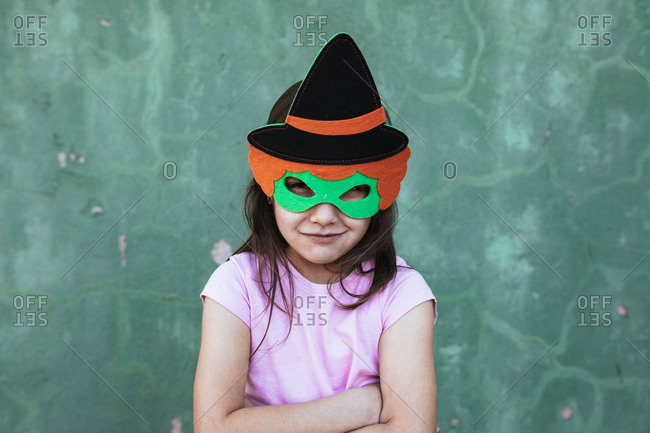 Calm child wearing creative costume of witch standing on street looking at camera at Halloween