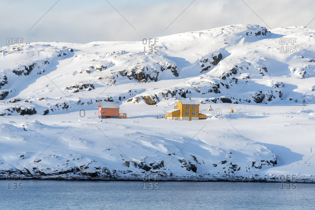 Isolated wood houses in the snow along the fjord during the arctic winter, Oksfjord, Troms og Finnmark, Northern Norway, Scandinavia, Europe