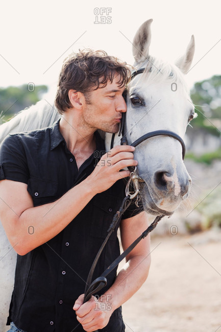 Man gives kiss to a white horse