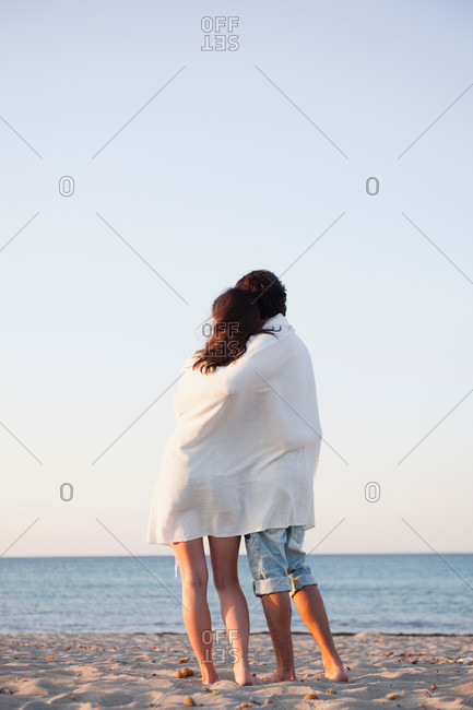 Couple cuddled up in beach towel