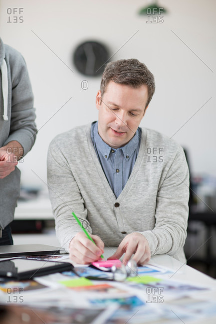 Mature man taking notes on desk in creative office