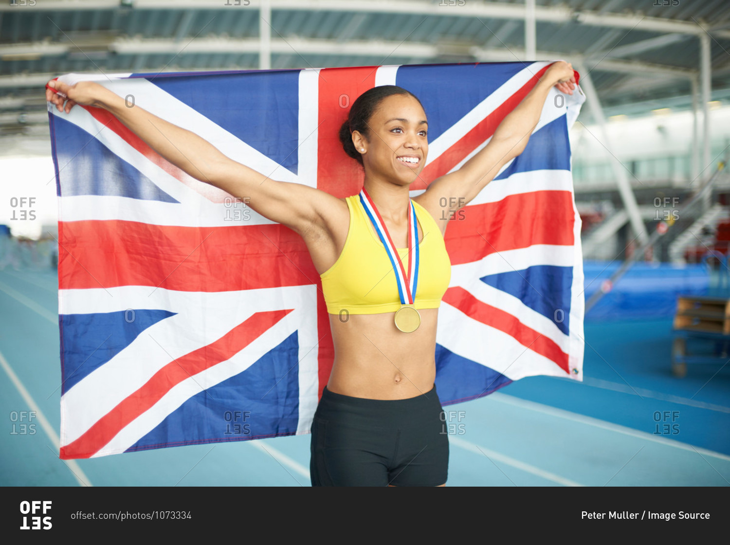 Young female athlete holding UK flag with gold medal