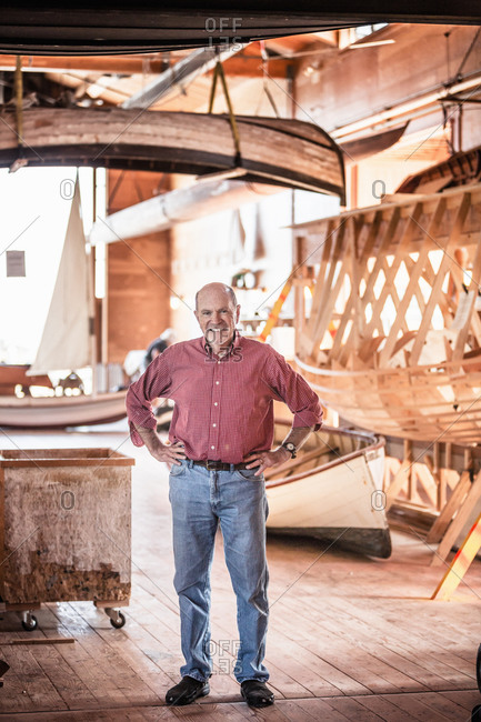 Senior man standing in boat-building workshop
