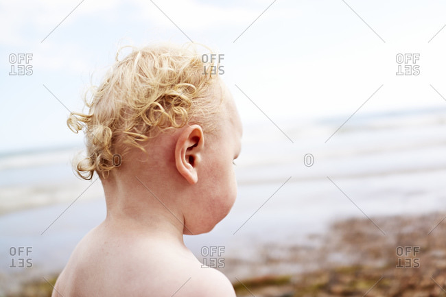 Rear view of bare shouldered male toddler at coast