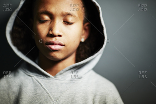 Boy wearing grey hooded top, eyes closed