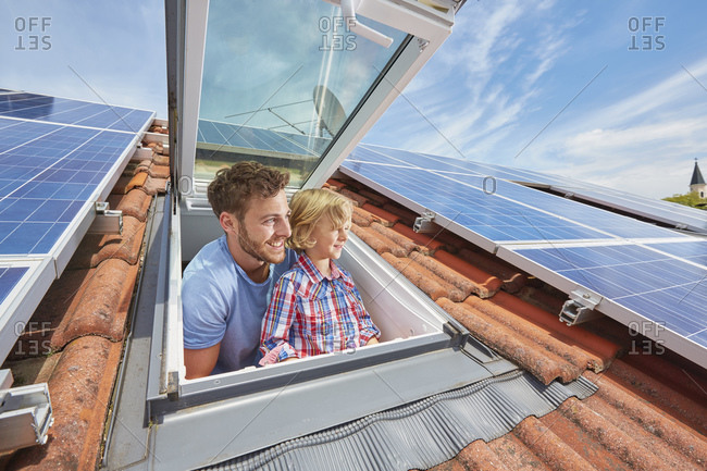 Father and son looking out of window of solar paneled roof