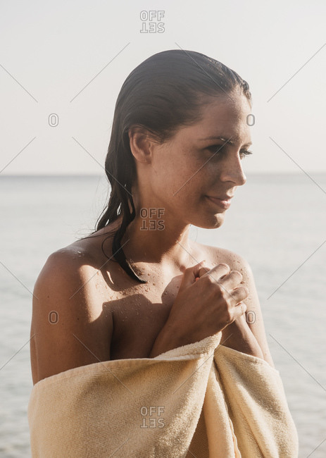 Portrait of beautiful young woman wrapped in towel at coast