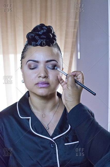 Bride having eyeshadow applied in hotel room