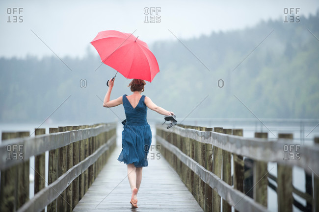 Woman on jetty with red umbrella