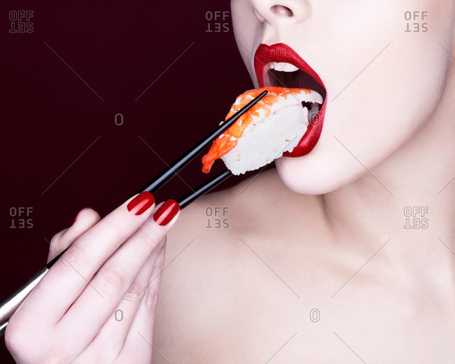 Woman with red lipstick eating sushi