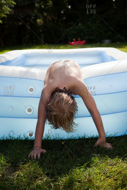 Boy leaning over paddling pool