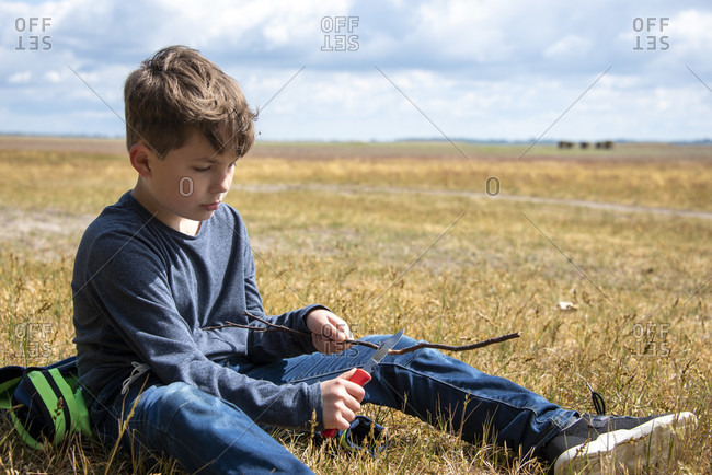 Boy carves a stick on the island of hiddensee