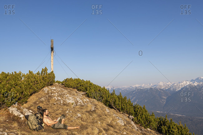 Mountaineers during the summit break on the simetsberg, enjoy the view of the karwendel mountains next to the summit cross