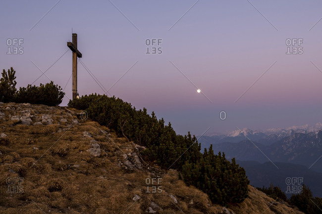 Simetsberg summit cross and in the background karwendel and estergebirge with a full moon in the evening after sunset