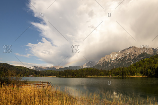 Rainbow after storm at lautersee near mittenwald in the bavarian alps. in the background the clouds and the karwendel mountains