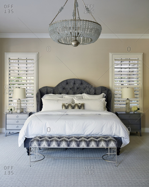 Beautiful chandelier above a large bed in the master bedroom of a modern home