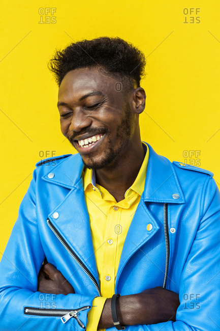 African American man with eyes closed in blue jacket smiling outdoors