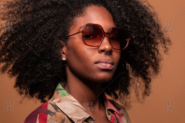 Confident Cuban woman with Afro hairstyle wearing sunglasses with floral shirt looking at camera