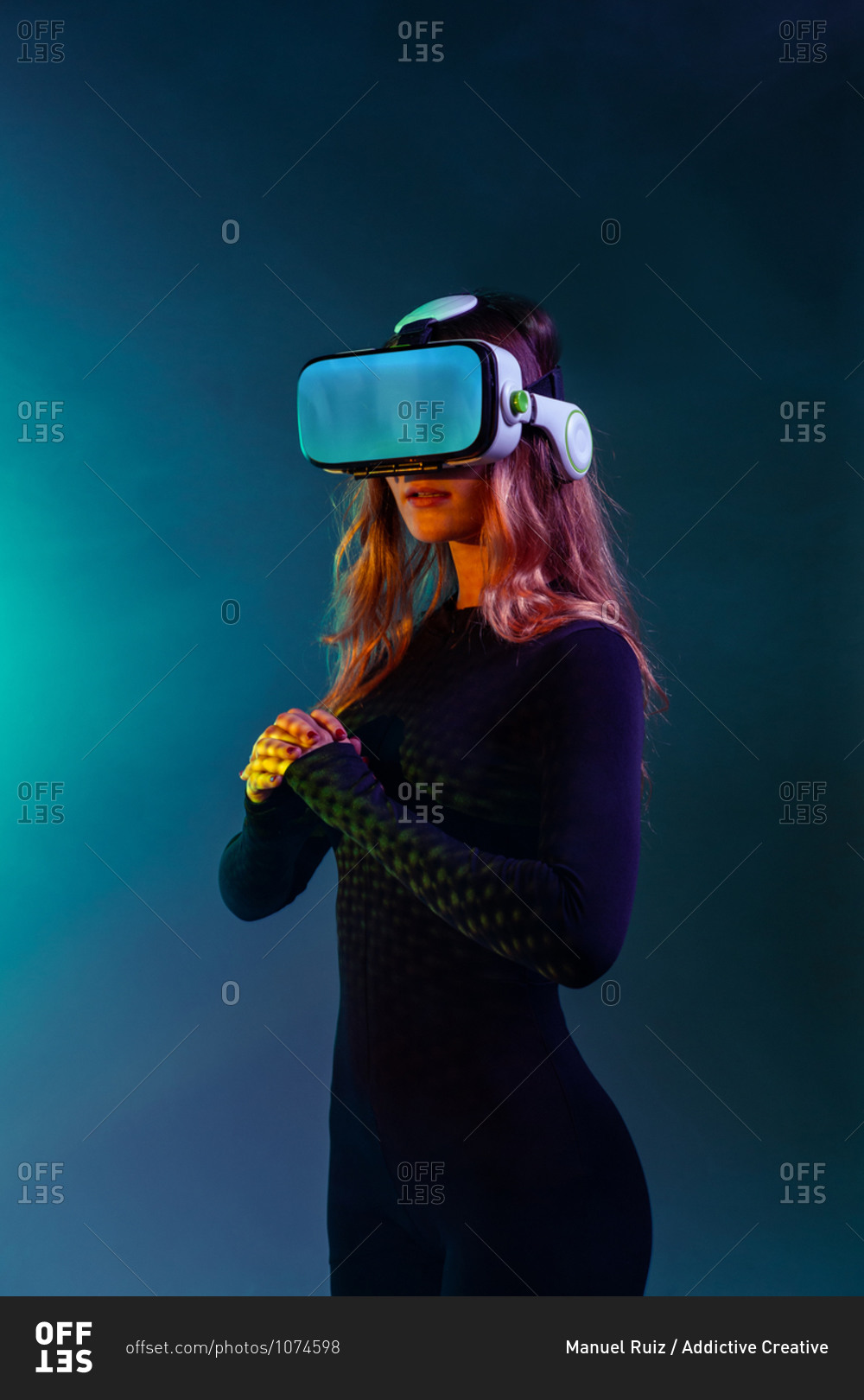 Young unrecognizable blonde woman standing wearing virtual reality headset on colorful blue neon illumination studio background
