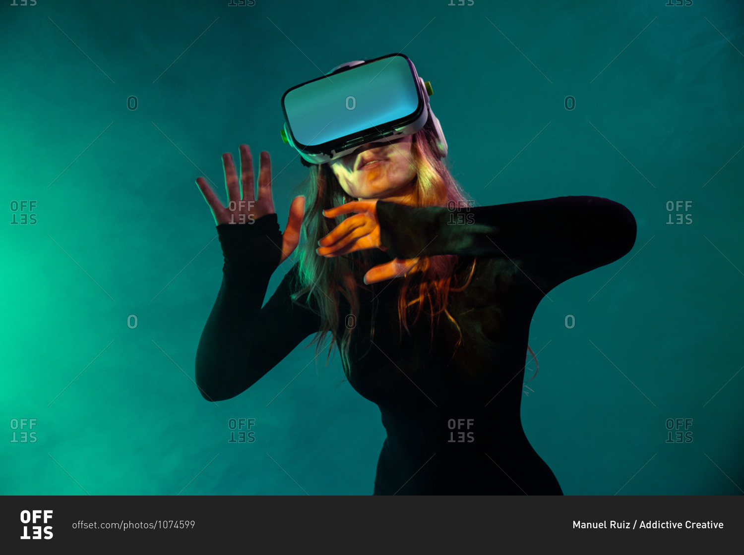Young unrecognizable blonde woman standing touching air and wearing virtual reality headset on colorful blue neon illumination studio background