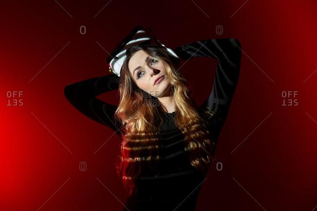 Young blonde woman wearing virtual reality headset standing on colorful red studio background looking away