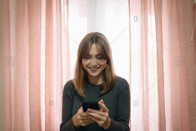Blonde girl using a mobile phone at home