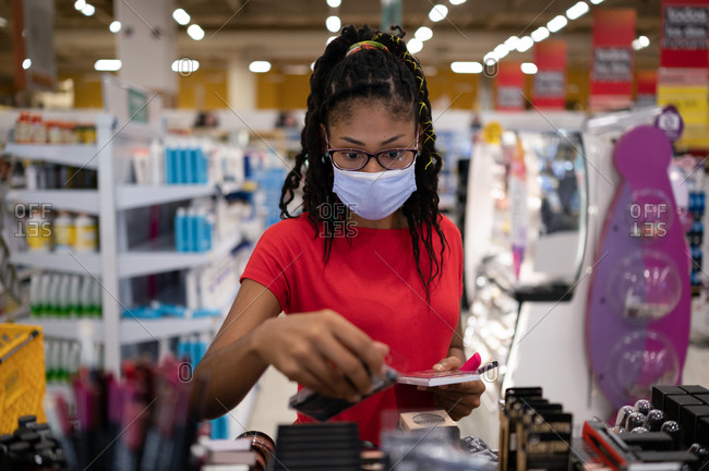 Afro latina young woman wearing a face mask shopping make up products