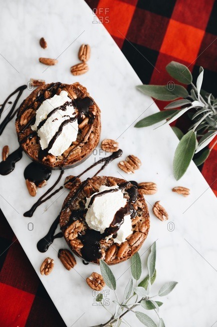 Two round pastries topped with whipped cream and pecans