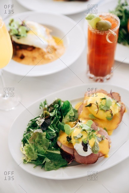 Eggs Benedict served on a table with a bloody Mary cocktail