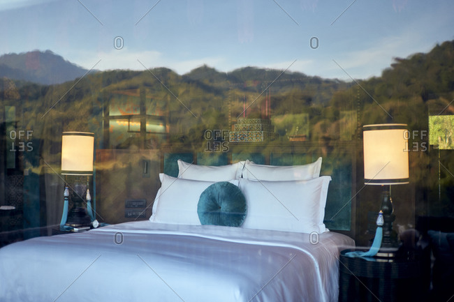 Luang Prabang, Laos - December 19, 2020: The bedroom in one of the hilltop tents, with mountains reflected through the sheer curtains at the Rosewood Hotel
