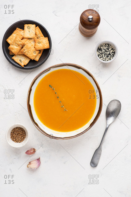 Overhead view of bowl of pumpkin soup served with cheese biscuits with pumpkin seeds