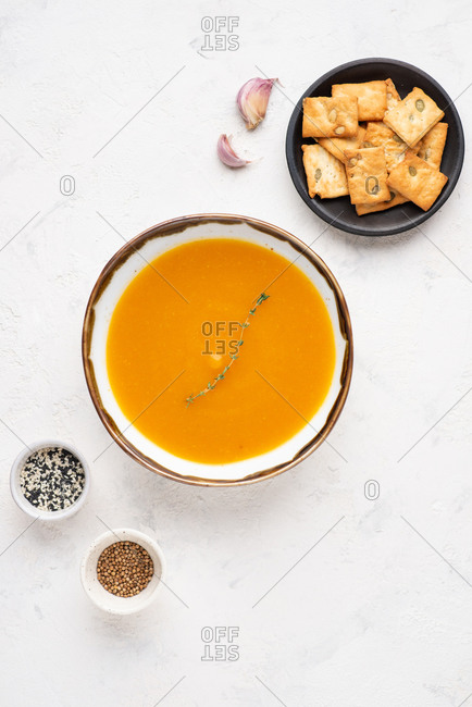Overhead view of bowl of pumpkin soup served with cheese biscuits with pumpkin seeds