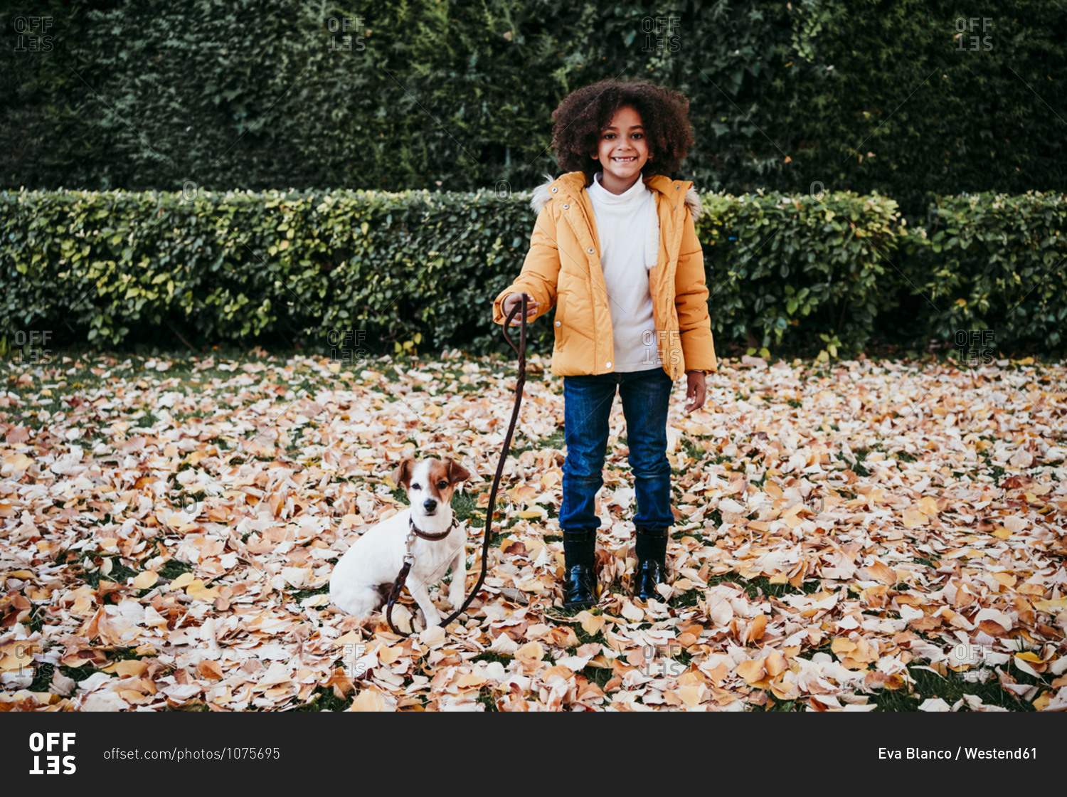 Smiling girl holding pet leash while standing by dog at park