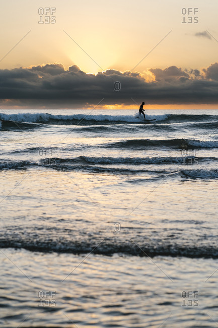 Silhouette man surfing with paddleboard on sea against sky during dawn