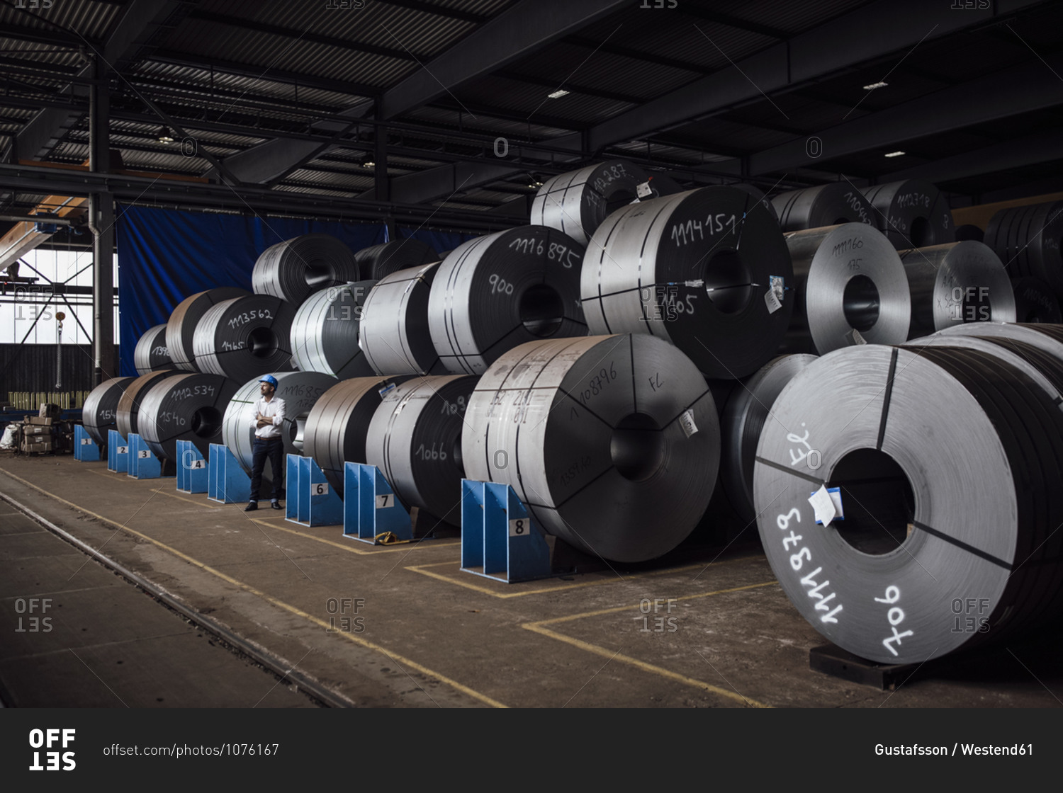 Businessman standing against steel rolls at factory