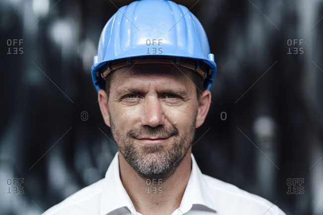 Smiling businessman wearing hardhat at factory