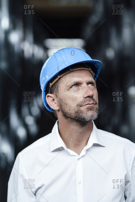 Businessman looking up while wearing hardhat at factory