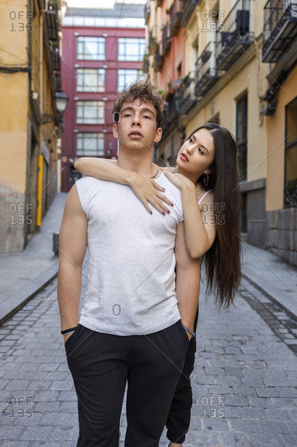 Young woman embracing man from behind while standing on footpath