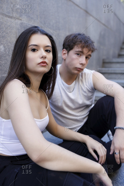 Young man and woman staring while sitting on staircase