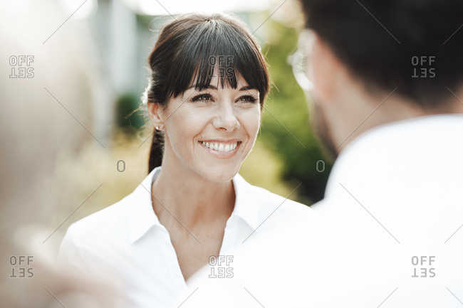 Smiling mature businesswoman with bangs looking at businessman during break
