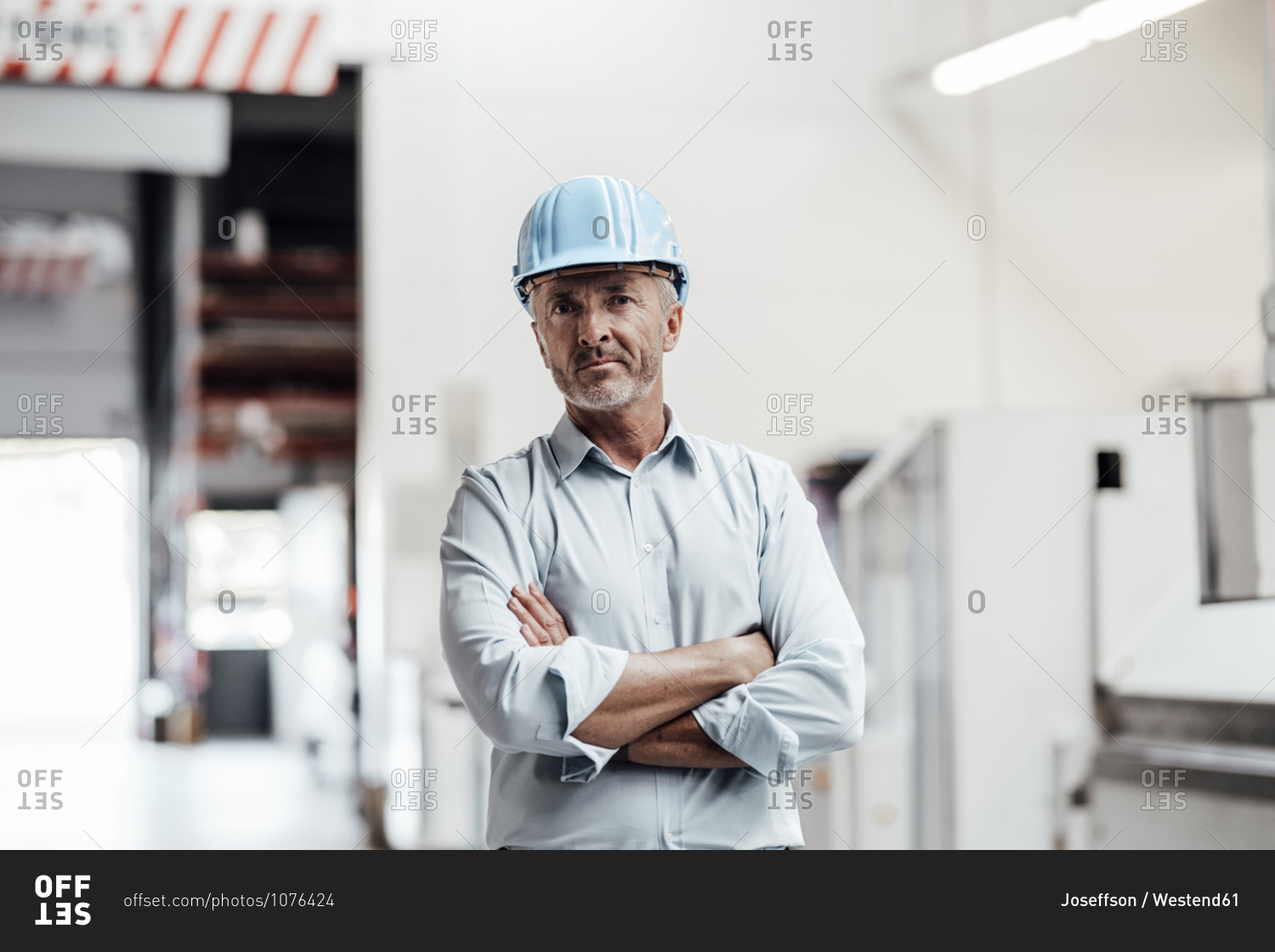 Confident male engineer standing with arms crossed in industry