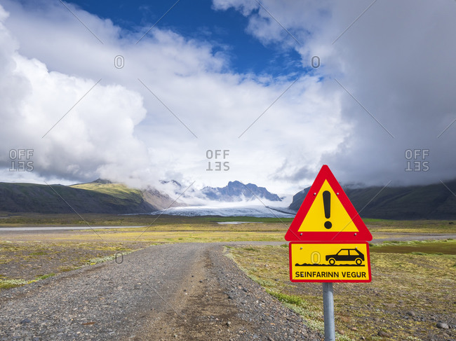 Sign by empty dirt road against cloudy sky at Svinafellsjokull- Iceland