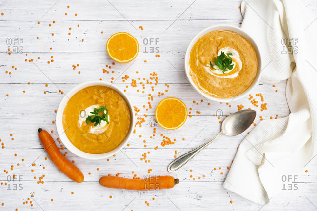 Two bowls of vegetarian lentil soup with carrots- orange juice- creme fraiche and parsley
