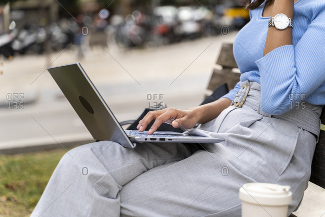 Woman surfing internet on laptop while sitting over bench