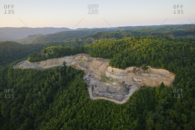 Aerial view of quarry surrounded by green forest at dawn
