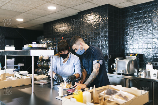 Male and female chefs preparing meal together at kitchen counter in restaurant