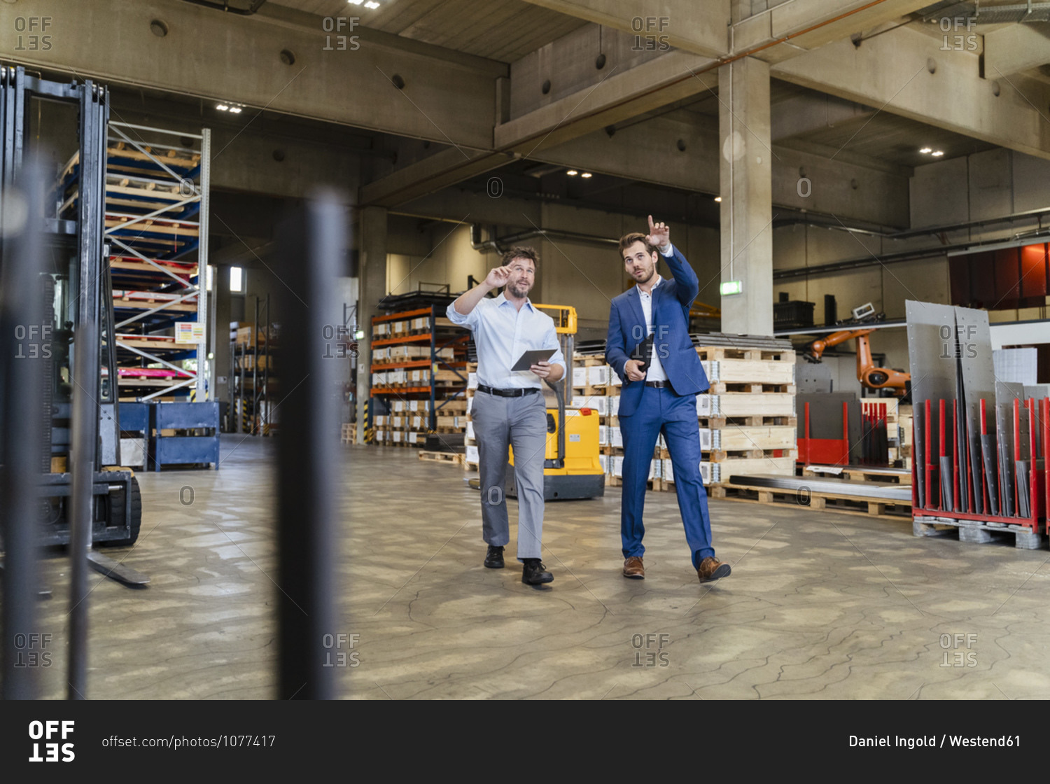 Businessman examining warehouse with colleague while walking at factory