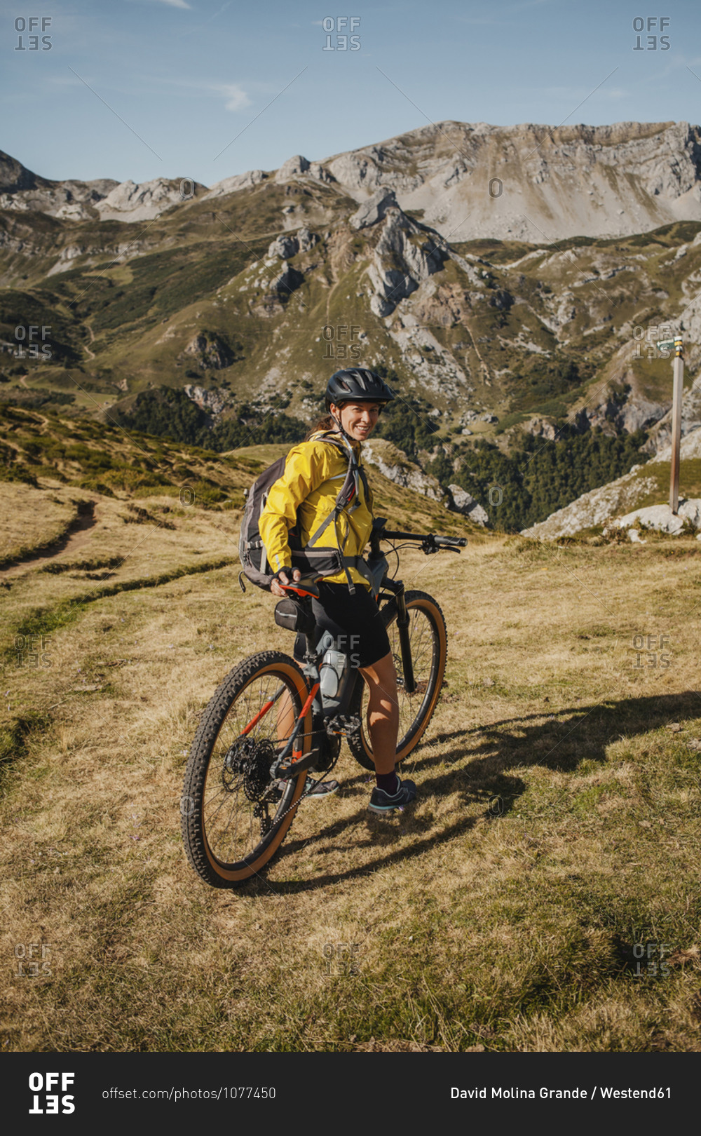 Smiling woman on electric mountain bike standing at Somiedo Natural park- Spain