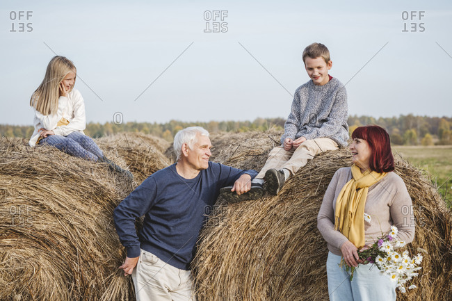 Grandparents with grandchildren sitting on hay bales