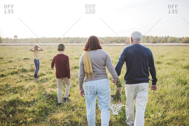 Grandparents spending time with grandchildren on field during weekend
